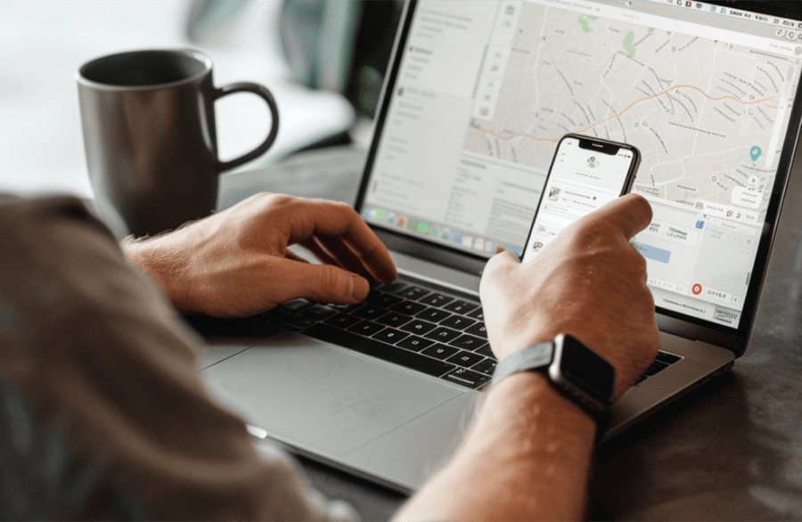 Man checking mobile map beside laptop and coffee