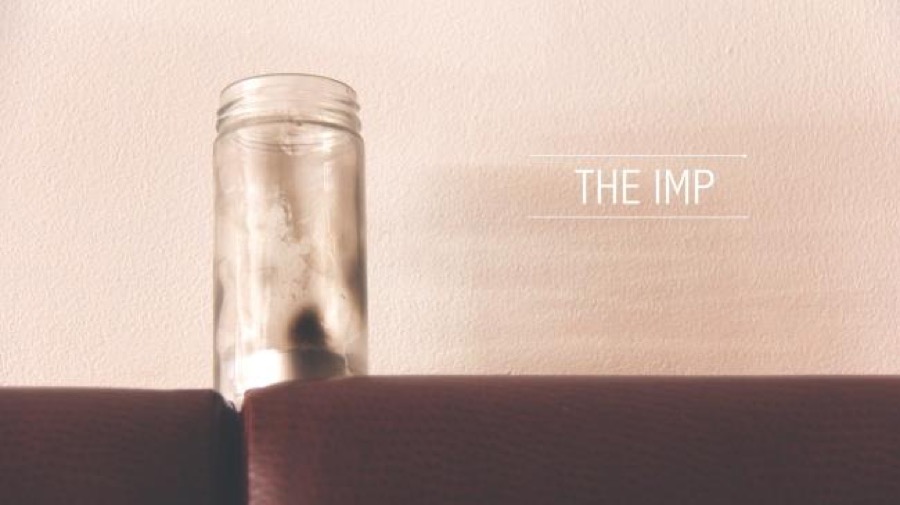 Glass jar on couch backrest with text 'THE IMP'